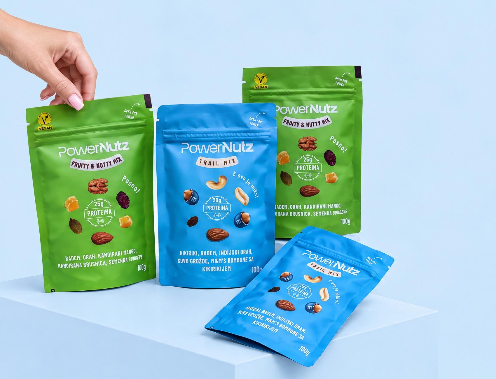 Ruka spušta kesice Trail mixa i Fruity and Nutty mixa na plavu kocku